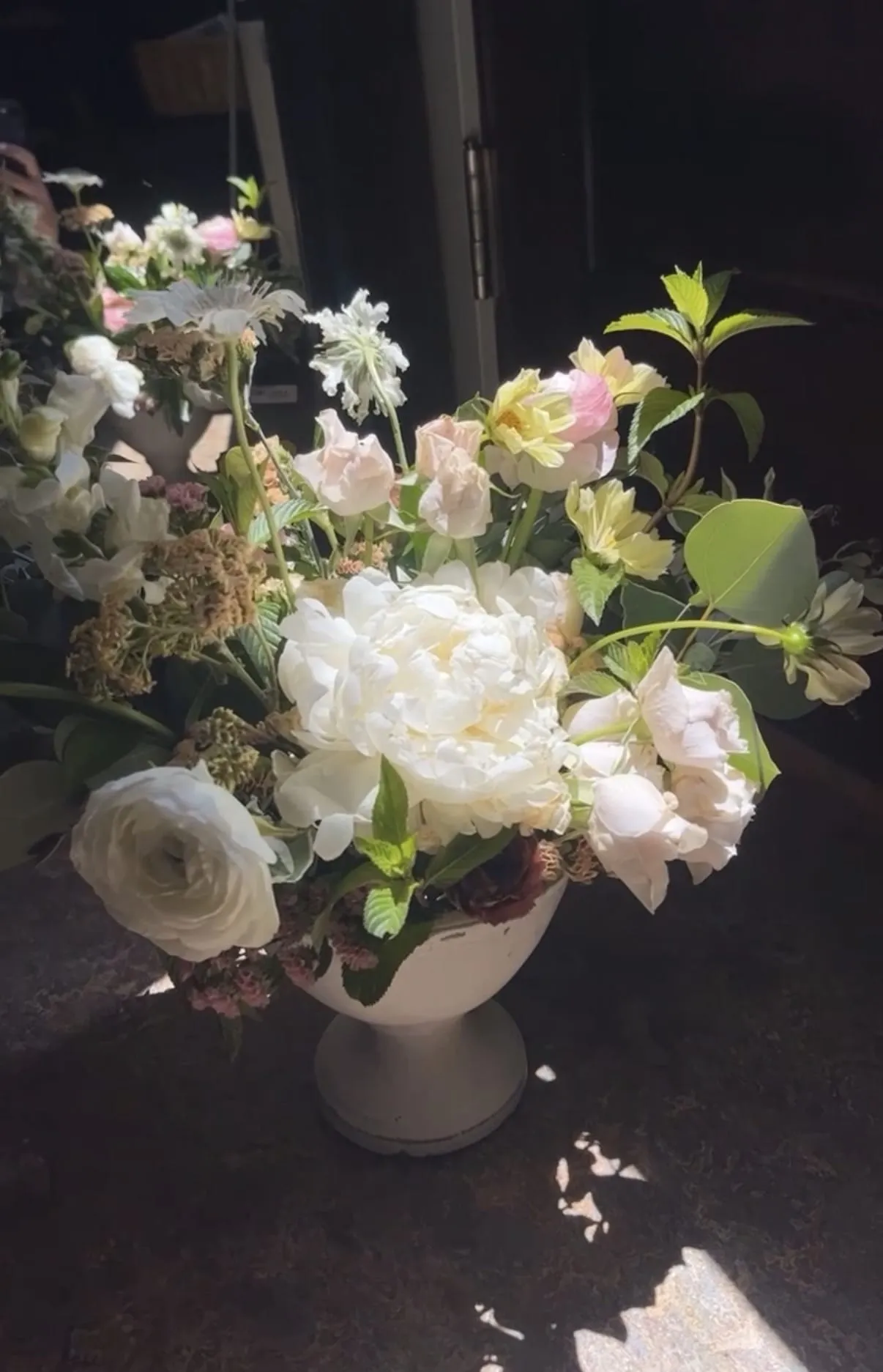 Blush and green floral arrangement styled low and lush in a ceramic bowl.